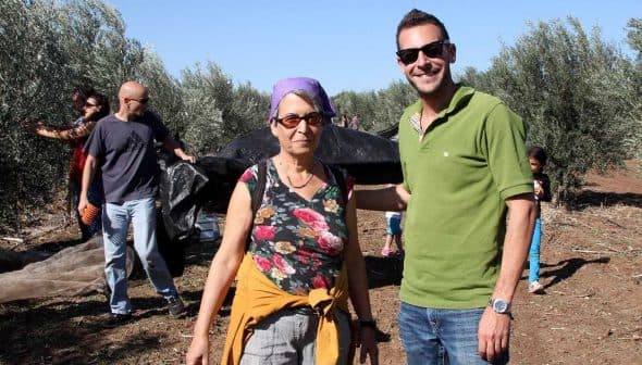 Two individuals posing for a photo in an olive grove during the olive harvesting process. - Olive Oil Times