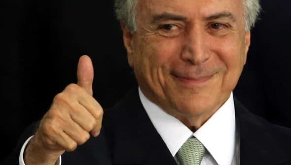 A man with gray hair and a suit giving a thumbs up gesture with a smile. - Olive Oil Times