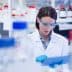 Female scientist wearing a lab coat and safety goggles using a tablet in a laboratory setting. - Olive Oil Times