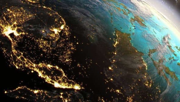 Satellite view of Earth at night showing illuminated regions and landmasses. - Olive Oil Times