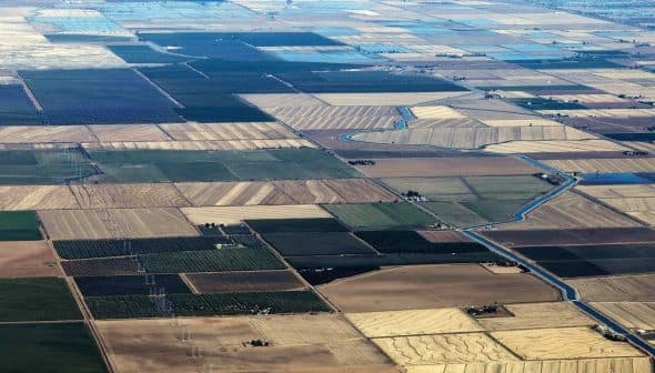 Aerial view of patchwork agricultural fields with varying colors and patterns. - Olive Oil Times