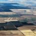 Aerial view of patchwork agricultural fields with varying colors and patterns. - Olive Oil Times