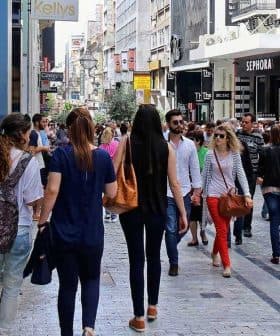Crowd of people walking on a busy pedestrian street with various shops and advertisements. - Olive Oil Times
