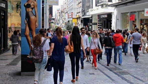 Crowd of people walking on a busy pedestrian street with various shops and advertisements. - Olive Oil Times