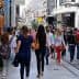 Crowd of people walking on a busy pedestrian street with various shops and advertisements. - Olive Oil Times