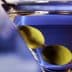 A close-up of a martini glass containing a clear drink and two green olives. - Olive Oil Times