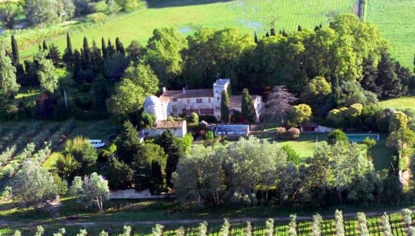 Aerial view of a vineyard with a large estate surrounded by trees and greenery. - Olive Oil Times