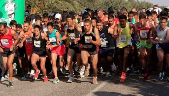 Group of runners starting a race, wearing various athletic gear and bib numbers. - Olive Oil Times