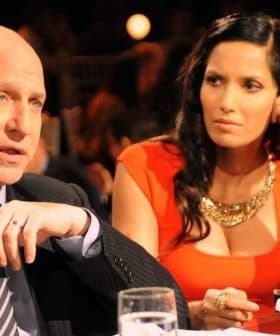 Two individuals seated at a table, one speaking and the other listening attentively in a dimly lit setting. - Olive Oil Times