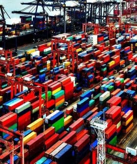 Aerial view of a container ship docked at a port surrounded by colorful shipping containers. - Olive Oil Times
