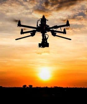 Silhouette of a drone flying against a sunset with clouds in the sky. - Olive Oil Times