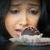 A woman with dark hair gazing intently at a chocolate dessert on a plate. - Olive Oil Times