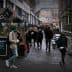 People walking through a narrow urban passageway with shops on either side. - Olive Oil Times