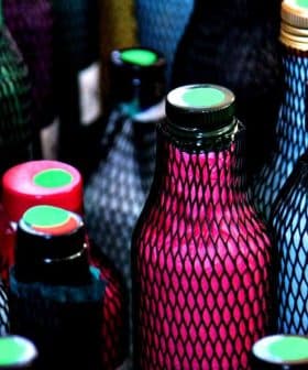 Various bottles with colorful netting and caps in a close-up view. - Olive Oil Times
