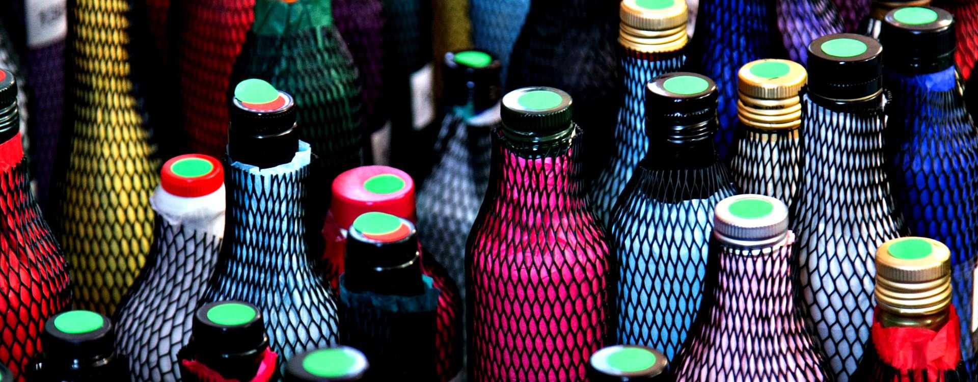 Various bottles with colorful netting and caps in a close-up view. - Olive Oil Times