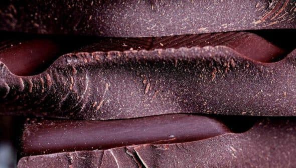 Close-up view of stacked layers of dark chocolate with a textured surface. - Olive Oil Times