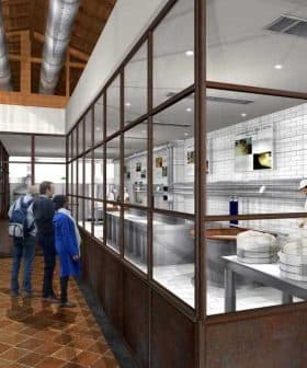 Interior view of a cheese production facility with workers and visitors observing the process. - Olive Oil Times