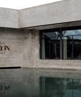 Modern architectural structure of Bodega Garzon with water reflection in front. - Olive Oil Times