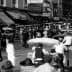 Black and white photograph of a busy boardwalk filled with pedestrians and horse-drawn carriages. - Olive Oil Times