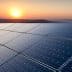 Row of solar panels reflecting sunlight during sunset with a distant horizon. - Olive Oil Times