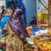 A busy market scene featuring vendors selling baked goods and shoppers browsing at stalls. - Olive Oil Times
