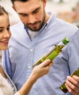 A couple inspecting olive oil bottles while shopping in a supermarket aisle. - Olive Oil Times