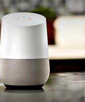 Google Home smart speaker with a white top and gray fabric base on a kitchen countertop. - Olive Oil Times