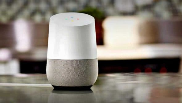 Google Home smart speaker with a white top and gray fabric base on a kitchen countertop. - Olive Oil Times