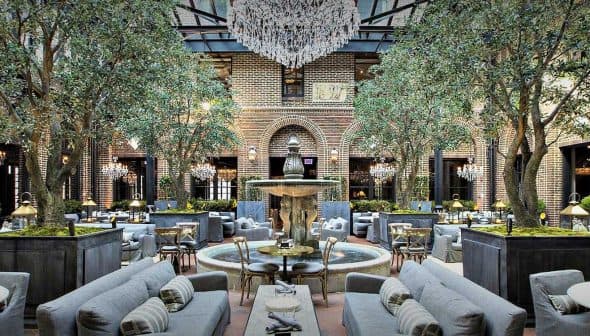 Indoor seating area featuring olive trees, a fountain, and elegant furniture arrangements. - Olive Oil Times