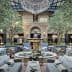 Indoor seating area featuring olive trees, a fountain, and elegant furniture arrangements. - Olive Oil Times