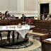 A legislative assembly room with attendees seated at tables during a meeting. - Olive Oil Times