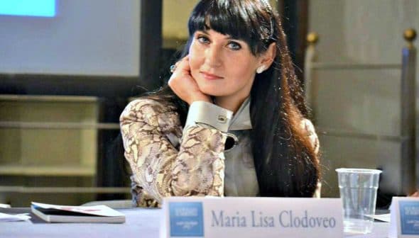 Maria Lisa Clodoveo seated at a table with her nameplate in front of her during an event. - Olive Oil Times