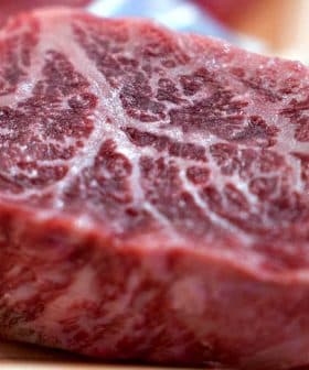 A close-up view of a raw beef cut showcasing marbling in the meat. - Olive Oil Times