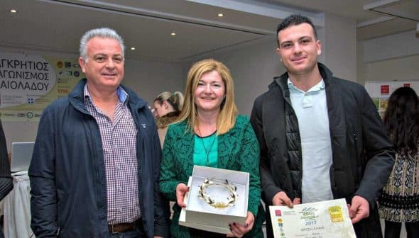 Three individuals posing with awards and a certificate at an event. - Olive Oil Times