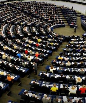 Interior view of the European Parliament with numerous members seated in a circular arrangement. - Olive Oil Times