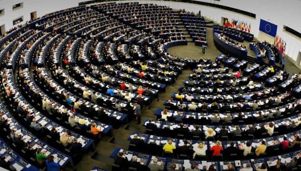 Interior view of the European Parliament with numerous members seated in a circular arrangement. - Olive Oil Times