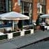Outdoor dining area with white umbrellas and tables at Fig & Olive restaurant. - Olive Oil Times