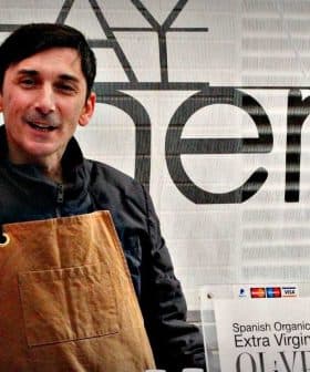 Man wearing an apron standing behind a table at an olive oil tasting event. - Olive Oil Times