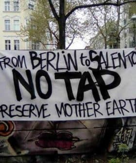 A protest banner reading 'From Berlin to Salento No Tap Preserve Mother Earth' displayed in an urban setting. - Olive Oil Times