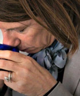 Individual smelling a small blue container during an olive oil tasting session. - Olive Oil Times