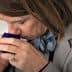Individual smelling a small blue container during an olive oil tasting session. - Olive Oil Times