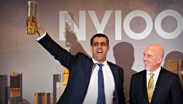 A man in a suit holding an award while standing next to another man in formal attire at an event. - Olive Oil Times