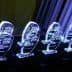 Row of crystal awards with engraved text on a dark surface illuminated by blue light. - Olive Oil Times