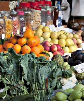 A market stall displaying a variety of fresh fruits and vegetables including oranges, apples, and greens. - Olive Oil Times