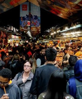 A busy marketplace filled with people browsing various stalls and displays of goods. - Olive Oil Times