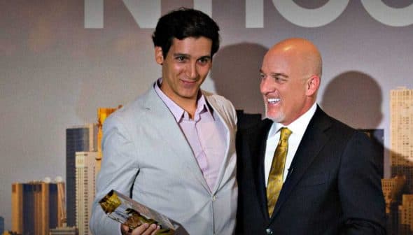 Two men standing together at an award ceremony, one holding a trophy and the other smiling. - Olive Oil Times