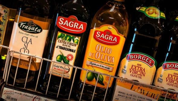 Various bottles of olive oil displayed on a shelf, including brands like Sagras and Borges. - Olive Oil Times