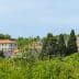 A village landscape featuring a church tower and traditional buildings among greenery. - Olive Oil Times