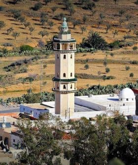 A minaret located in a rural area, surrounded by olive trees and agricultural land. - Olive Oil Times