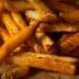 A pile of golden brown French fries seasoned with spices on a piece of parchment paper. - Olive Oil Times